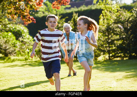 Frère et sœur s'exécutant dans le jardin ensoleillé Banque D'Images