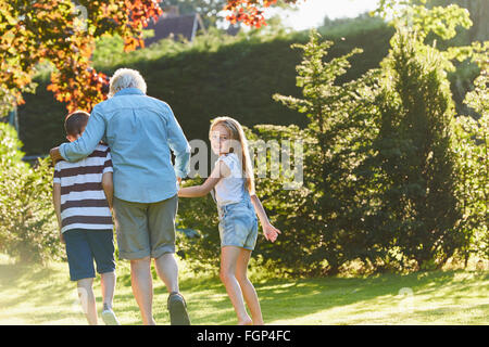 Portrait smiling girl walking avec grand-mère et son frère dans le jardin Banque D'Images