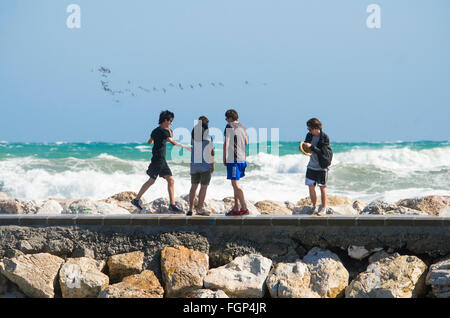 Adolescents s'amusant sur une jetée à plage, regardant l'océan de hautes vagues, Costa del Sol, Espagne. Banque D'Images