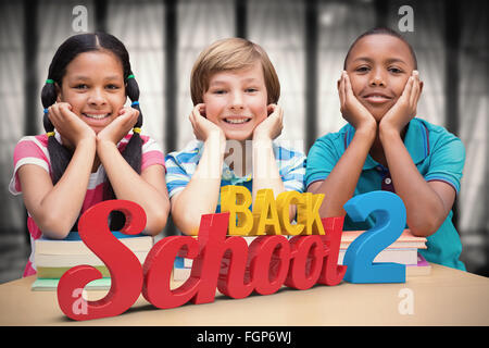 Image composite de cute pupils looking at camera in library Banque D'Images