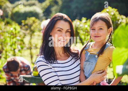 Portrait of smiling mother and daughter hugging in sunny garden Banque D'Images