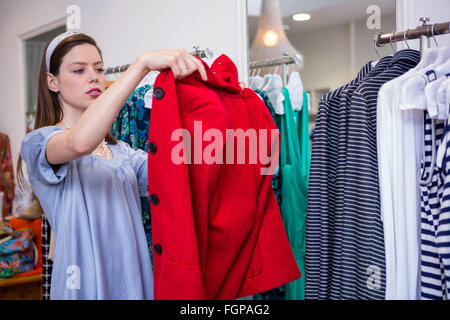 Brunette essayant sur un manteau rouge Banque D'Images