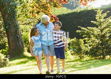 Grand-mère et ses petits-enfants marcher dans le jardin ensoleillé Banque D'Images
