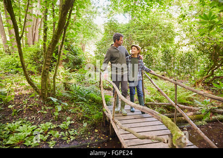 Père et fils traversant la passerelle en forêt Banque D'Images