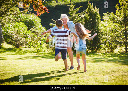 Petits-enfants courir à grand-mère dans le jardin ensoleillé Banque D'Images