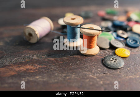 Bobines de fils et de boutons sur la vieille table en bois Banque D'Images