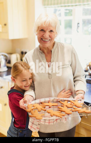 Portrait smiling grandmother and granddaughter baking gingerbread cookies Banque D'Images