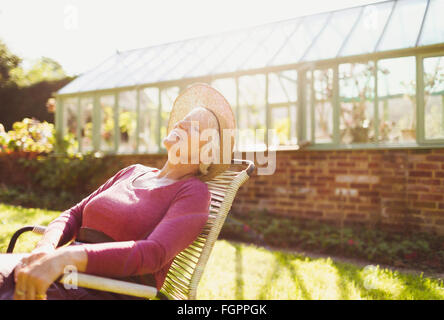 Carefree senior woman relaxing hors serre ensoleillée Banque D'Images