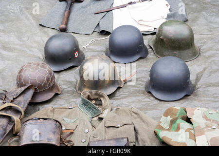 Seconde guerre mondiale re-enactment. Six types de WW2 casque allemand stahlhelm, étain, disposés sur le sol. Banque D'Images