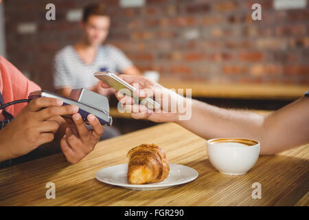 Payer pour un croissant et un café avec son smartphone Banque D'Images