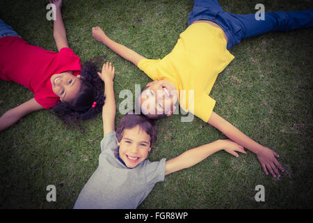 Cute pupils lying on grass smiling Banque D'Images