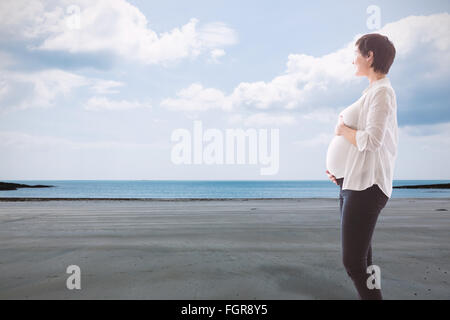 Image composite de femme enceinte debout sur un tapis sur fond blanc Banque D'Images