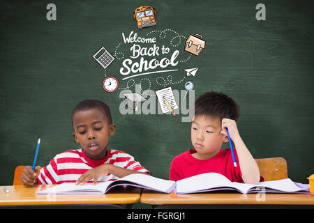 Image composite de cute pupils écrit at desk in classroom Banque D'Images