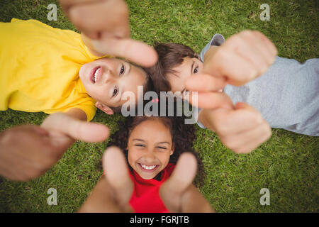 Cute pupils lying on grass smiling Banque D'Images