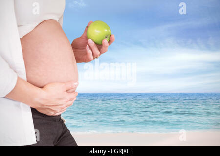 Image composite de midsection of pregnant woman holding green apple Banque D'Images