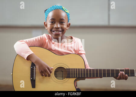 Smiling élève qui joue de la guitare dans une salle de classe Banque D'Images