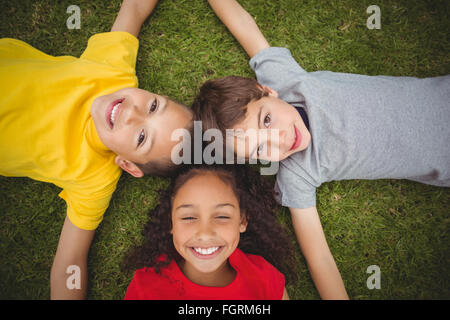 Cute pupils lying on grass smiling Banque D'Images