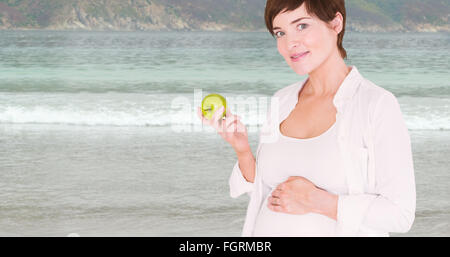 Composite image of pregnant woman holding green apple Banque D'Images