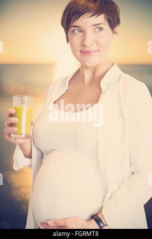 Composite image of pregnant woman holding glass of orange juice Banque D'Images