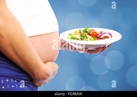 Image composite de pregnant woman eating a salad Banque D'Images