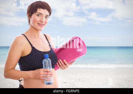 Image composite de pregnant woman holding water bottle et tapis d'exercice Banque D'Images