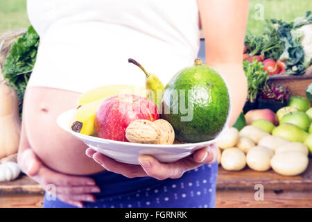 Image composite de femme enceinte montrant des fruits et légumes Banque D'Images