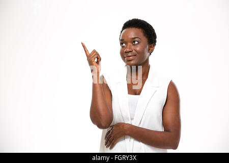 Cheerful pretty african american woman et pointant vers le haut sur fond blanc Banque D'Images