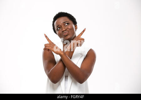 Confus african american woman pointant vers le haut avec les deux mains sur fond blanc Banque D'Images