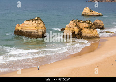 Personne qui marche sur la plage avec des rochers de grès, Praia da Rocha, Algarve, Portugal Banque D'Images