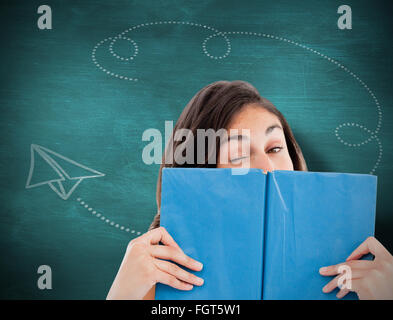 Image composite de portrait d'un étudiant avec un clin derrière un livre bleu Banque D'Images