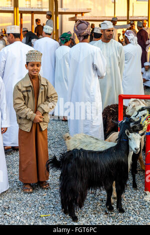 Un garçon à la recherche après ses chèvres au marché aux bestiaux de Nizwa, vendredi, Ad Dakhiliyah, Région de l'Oman Banque D'Images