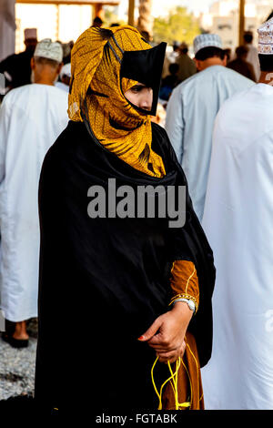 Un Omanais femme vêtue de la Traditionnelle Costume Omaniya au marché de l'élevage Vendredi à Nizwa, Al Dakhiliyah, Région de l'Oman Banque D'Images