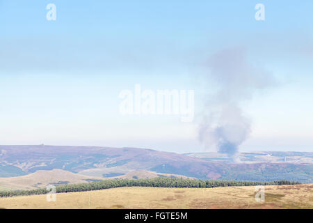 La fumée s'élevant dans le ciel d'une lande lointain incendie dans la région de Derwent Moors, Derbyshire Peak District, à la frontière du Yorkshire, England, UK Banque D'Images