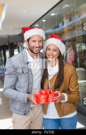 Young happy couple holding heart avec des boîtes en forme de chapeaux de noël sur leurs chapeaux Banque D'Images