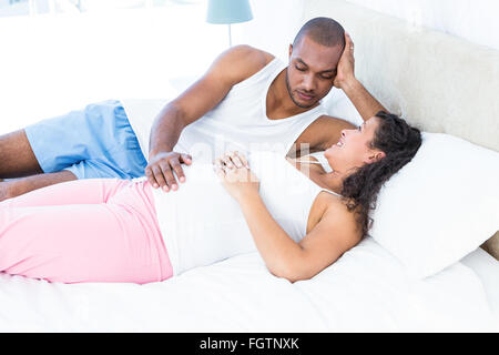 Happy pregnant wife relaxing with mari on bed Banque D'Images