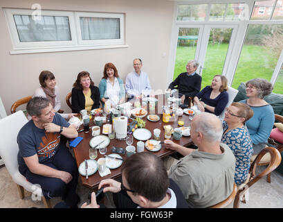 Un groupe d'amis adultes âgés de 50 ans ayant le petit déjeuner assis à table dans une chambre de l'intérieur, UK Banque D'Images