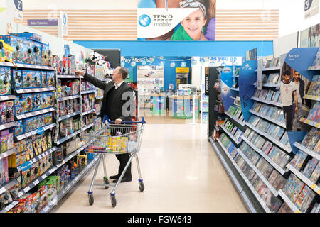 Un homme shopping dans un supermarché Tesco entertainment allée, UK Banque D'Images