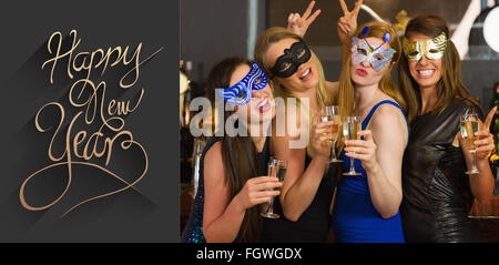 Image composite de l'attractive women wearing masks holding champagne Banque D'Images