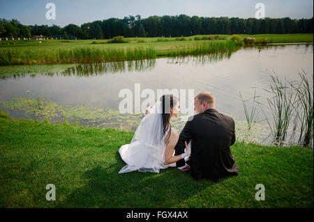 Le marié et la mariée à pied près du lac le jour de leur mariage Banque D'Images