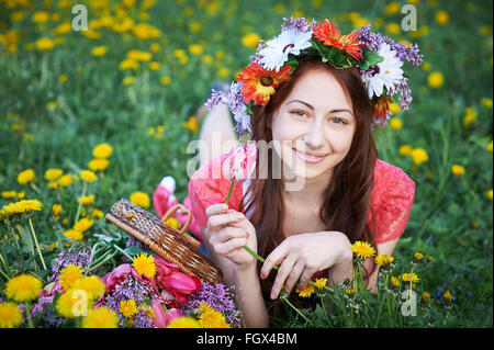 Femme heureuse avec couronne posé sur une prairie avec un bouquet de fleurs Banque D'Images