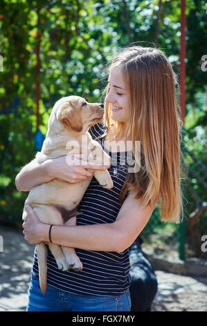 Femme blonde jouant avec un chiot Labrador blanc Banque D'Images