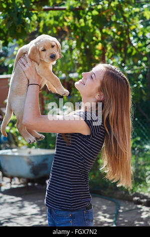 Belle femme jouant avec un chiot Labrador blanc Banque D'Images