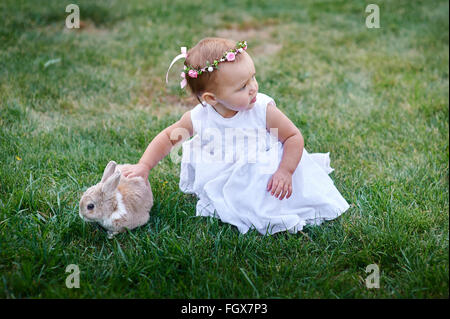 Petite fille jouant avec un lapin sur l'herbe Banque D'Images