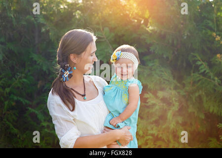 Maman tient dans ses bras sa fille et joue sur la nature Banque D'Images