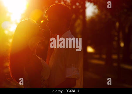 Jeune couple hugging silhouette et regarder à l'extérieur sur le coucher du soleil Banque D'Images