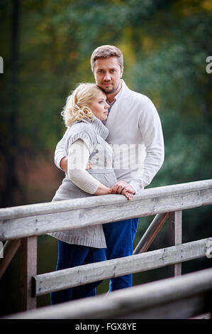 Jeune femme blonde avec son mari dans le parc sur le pont Banque D'Images