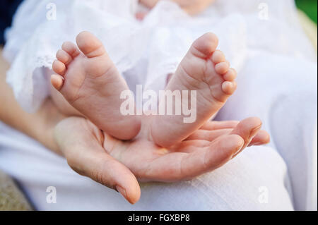 Mère main tenant les petits pieds de bébé Banque D'Images