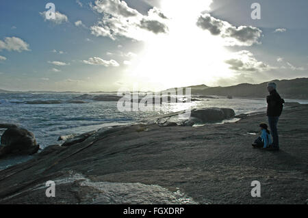 Père et fille regarder la marée montante au coucher du soleil, près de l'Elephant Rocks, William Bay National Park, au Danemark, en Australie occidentale. Banque D'Images