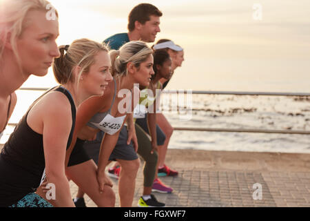 Porteur debout sur la ligne au départ d'une course. Groupe de jeunes de la formation pour le marathon course sur route par la mer. Banque D'Images