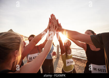 L'équipe d'athlétisme avec leurs mains empilées ensemble célébrer la réussite. Les coureurs de marathon, offrant un rapport 5. Banque D'Images